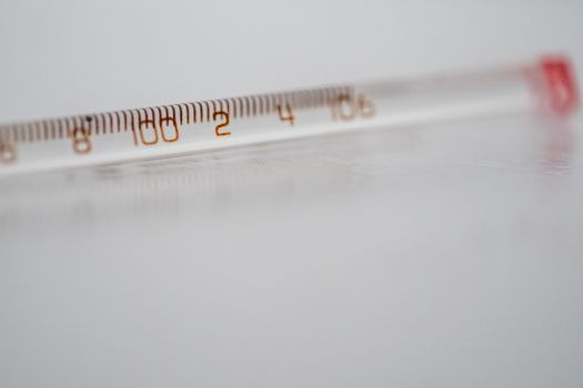 Detailed close-up of a mercury glass thermometer on a white surface, showing temperature measurements.