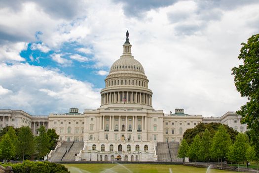 View of United States Capitol with neoclassical architecture against a cloudy sky in Washington D.C.