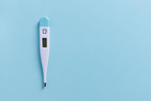 Close-up of a digital thermometer on a light blue background with copyspace.